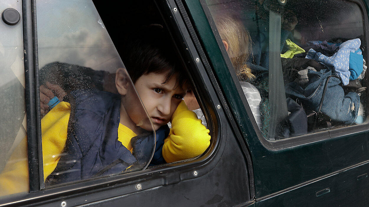 Armenian boy in car loaded with belongings as he flees his ancestral home of Artsakh (Nagorno-Karabakh)
